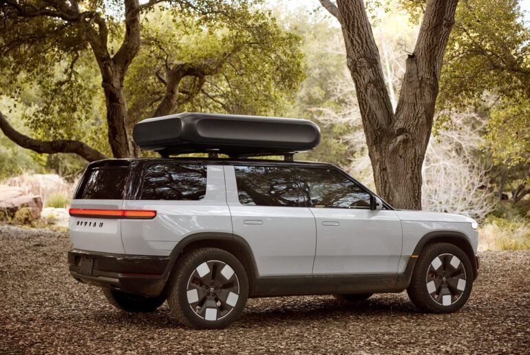 Image shows the Rivian R2 vehicle in a wooded area.