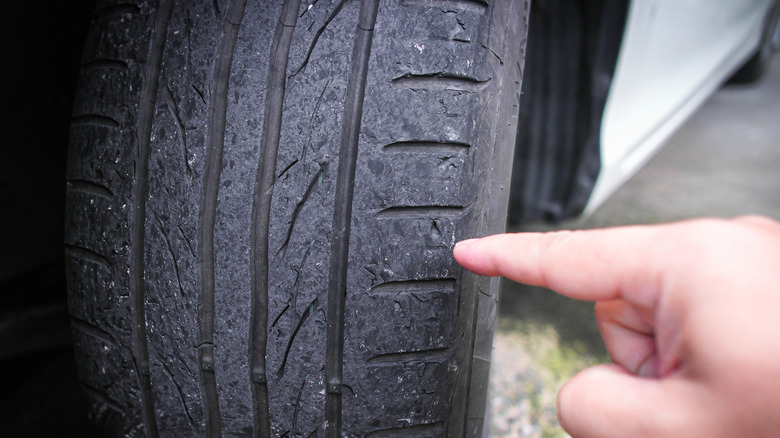 finger pointing to worn out tread on a tire