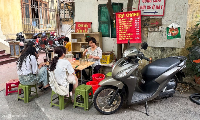 Nguyet Nga, 63, at her iced tea stall, where she always parks her gasoline motorbike beside her. Photo by VnExpress/Minh Quan