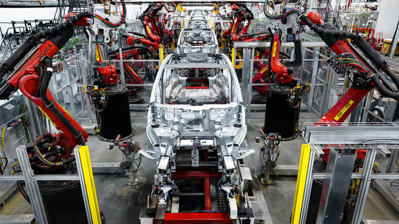 A vehicle is assembled with robot arms in a Tesla factory.