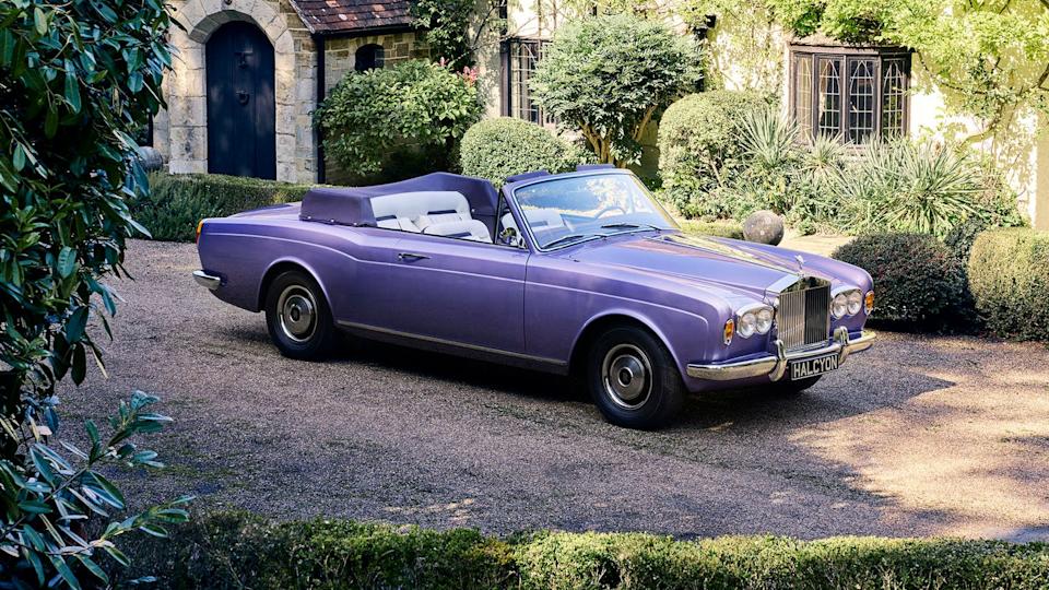 Convertible luxury car parked in a garden setting.