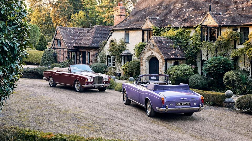 Two vintage cars parked in front of a charming cottage.