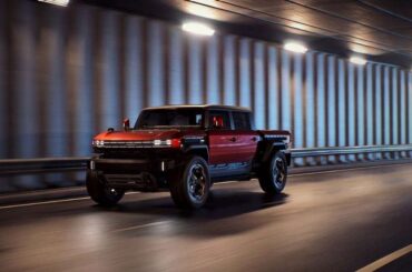 Red GMC Hummer HX truck concept driving through a tunnel in a front three-quarter action view.