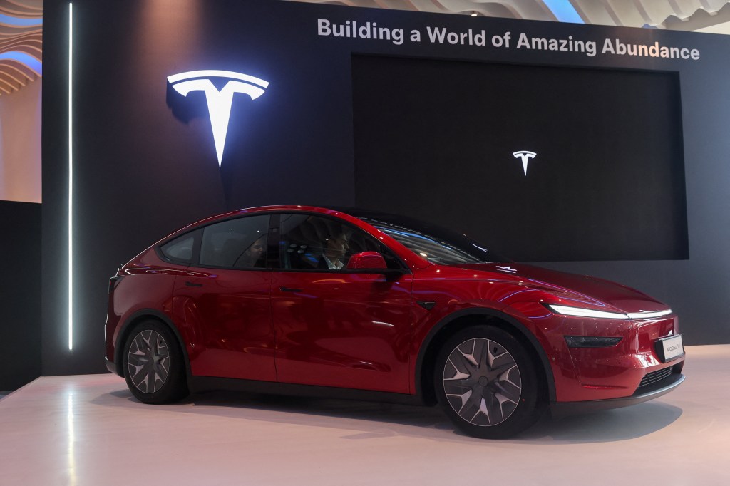 A red Tesla Model Y L variant electric vehicle on display at a launch event.