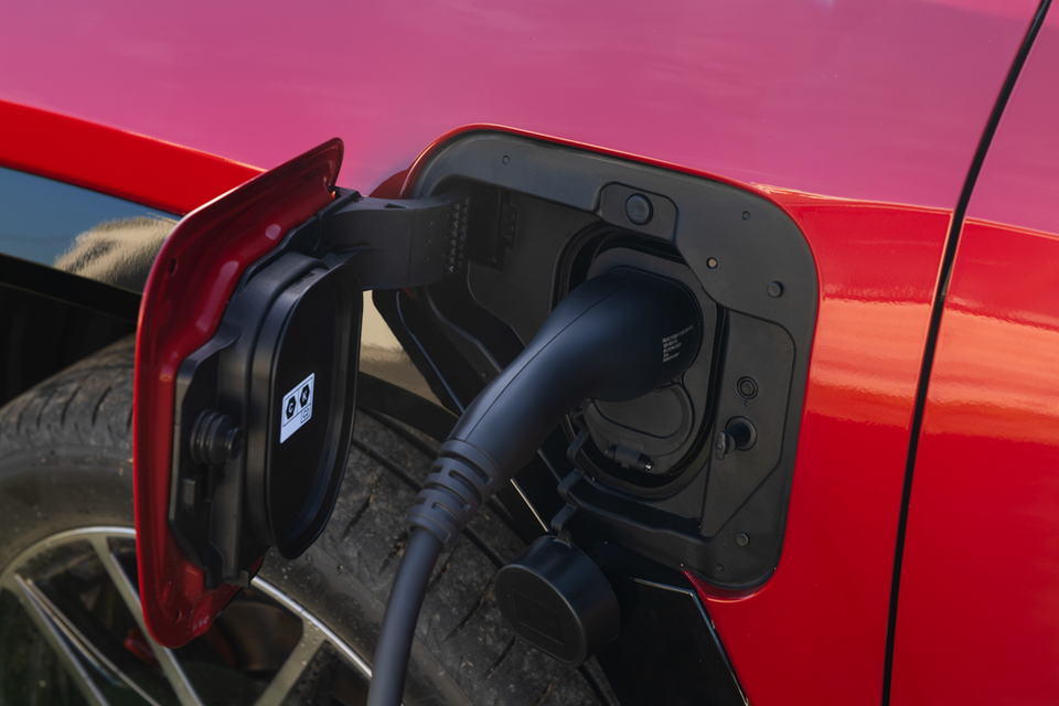 Close-up of the charging port on a red Toyota RAV4 PHEV with a charging cable plugged in